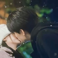 a man and woman kissing each other in front of some water droplets on the ground