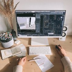 a person sitting at a desk in front of a computer monitor with architectural drawings on it