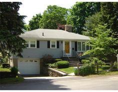 a gray house with trees and bushes around it