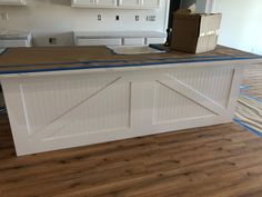 an unfinished kitchen counter with white cabinets and blue tape on the top is being painted