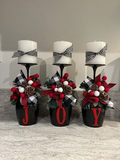 three black vases with red and white decorations on them, one has a candle holder that says joy