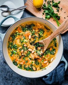 a white bowl filled with soup next to a cutting board and lemons on the side