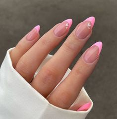 a woman's hand with pink and white manicures on her nails, in front of a gray background