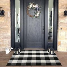 a black and white checkered rug is in front of a door with a wreath on it