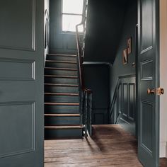 an open door leading to a dark room with stairs and wooden flooring in front of it