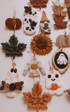 many different fall and halloween decorations are on a white surface with leaves, pumpkins, acorns, and skulls