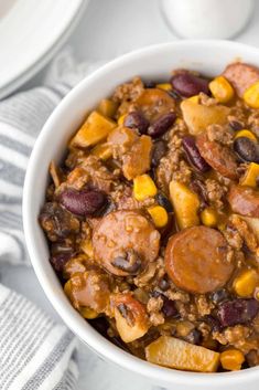 a white bowl filled with chili and sausage casserole on top of a table