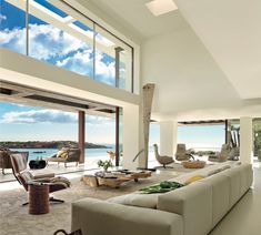 a living room filled with lots of furniture next to a large open window overlooking the ocean