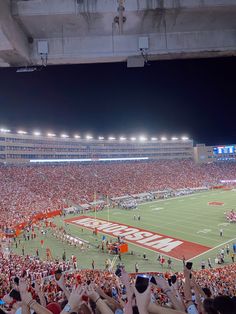 a football stadium full of people and fans with their hands up in the air,