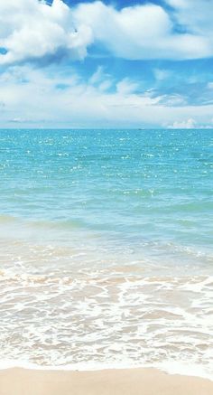 an ocean view with waves crashing on the beach and clouds in the blue sky above