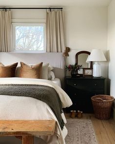 a bed sitting in a bedroom next to a window with drapes on the windowsill