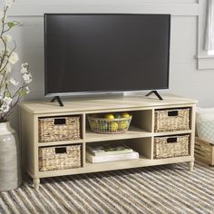 a flat screen tv sitting on top of a wooden entertainment center next to a vase with flowers