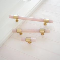 two white and gold bathroom handles on the side of a bathtub with pink marble