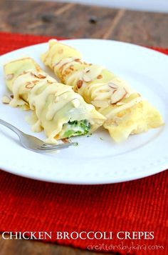 a white plate topped with crepes covered in cheese and sauce on top of a red place mat