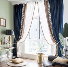 a living room filled with furniture and a large window covered in blue curtained drapes