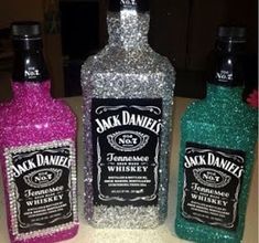 three bottles of jack daniels gin on a counter with glitter in the top and bottom