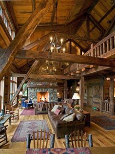 a living room filled with lots of furniture and wooden beams on the ceiling is lit by chandeliers