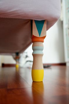 a wooden toy under a bed on top of a hard wood floor