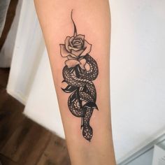 a snake wrapped around a rose tattoo on the arm