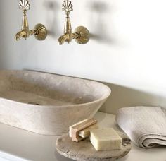 a bathroom sink with soap and two faucets on the wall