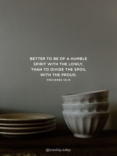 a stack of white plates sitting on top of a wooden table next to a wall