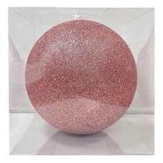 a pink ornament in a clear box with glitter on the outside and inside