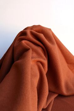 an orange cloth is laying on top of a white surface with the fabric pulled back