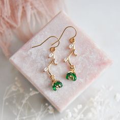 "Emerald Green Flower Earrings // Gold Filled Earrings // Boho Bridal Earrings // Floral Earrings // May Birthstone // Leaf Earrings // Birthday Gift // Bridesmaids Earrings // Four Leaf Clovers  :: Provide an enchanting effect with these lush emerald green floral earring for your woodland wedding :: These emerald green flower earrings are a delicate and feminine design perfect for any boho wedding attire or for adding a little sparkle to your next special occasion. The tiny verdant flower petals are created with faceted glass and are reminiscent to four leaf clovers. These dainty flowers are secured to golden stems featuring small cubic zirconia leaves. The lush green flower earrings are light weight and suspended from comfortable 14k gold filled earrings.  Whether adding these flower ear Flower Shaped May Birthstone Jewelry, Delicate Green Jewelry With Birth Flower, Elegant Flower Jewelry For May Birthstone, Delicate Green Birth Flower Jewelry, Green Dangle Earrings For Mother's Day, Green Dainty Dangle Earrings, Elegant Green Earrings For Mother's Day, Dainty Green Dangle Earrings, Green Dangle Flower Earrings For Gift