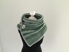 a green and white crocheted scarf on top of a mannequin head