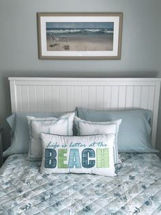 a bed with blue and white pillows on it next to a framed picture above the headboard