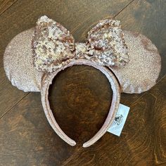 a minnie mouse ears headband with gold sequins on the ears and a tag attached to it