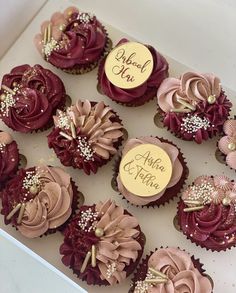 cupcakes decorated with chocolate frosting and flowers are displayed on a white box