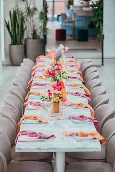 a long table is set with place settings and flowers