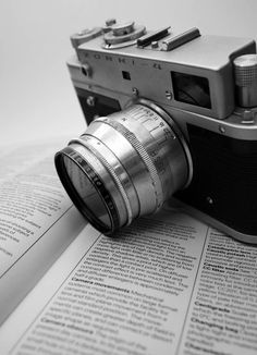 an old fashioned camera sitting on top of a book next to it's lens