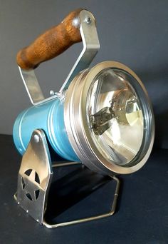 a metal and blue light with a wooden handle sitting on top of a black table