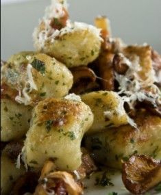 close up view of pasta with mushrooms and parmesan cheese on the top, ready to be eaten