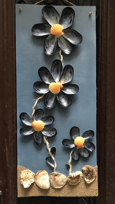 a blue plaque with seashells and flowers hanging from it's front door