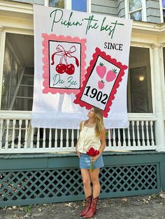 a woman standing in front of a sign with cherries on it