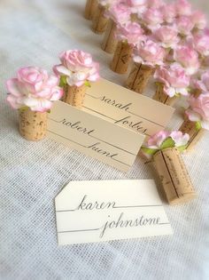 small flowers are placed in corks with name tags attached to them on a table