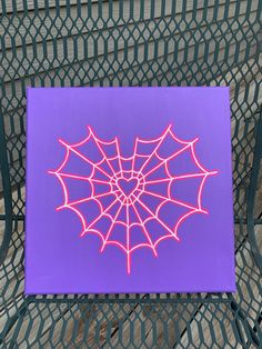 a purple canvas with a spider web design on it sitting on a metal park bench