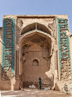 a woman standing in front of a building with blue and green decorations on the walls