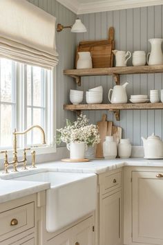 a kitchen filled with lots of white dishes and cups on top of wooden shelves next to a window