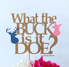 a cake topper that says, what the buck is it doe? with some flowers