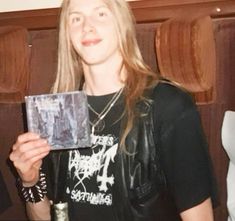 a woman holding up a cd in front of her face and wearing a black shirt