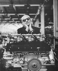 an old photo of a man with sunglasses on his head sitting in front of a large engine