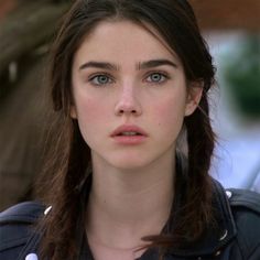 a close up of a person wearing a jacket and looking at the camera with a serious look on her face