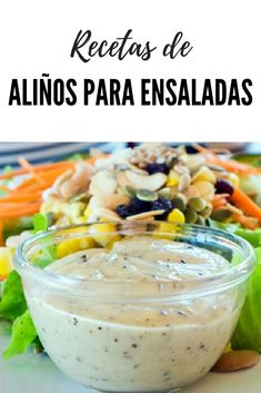 a salad with dressing in a glass bowl on top of a white plate next to lettuce and carrots