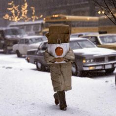 a person walking in the snow with an apple on their head and a bag over his shoulder