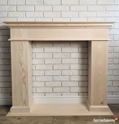 a white brick wall with a wooden fireplace mantel in the middle and wood trim around it