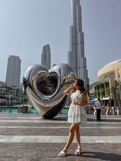 a woman standing in front of a heart shaped sculpture